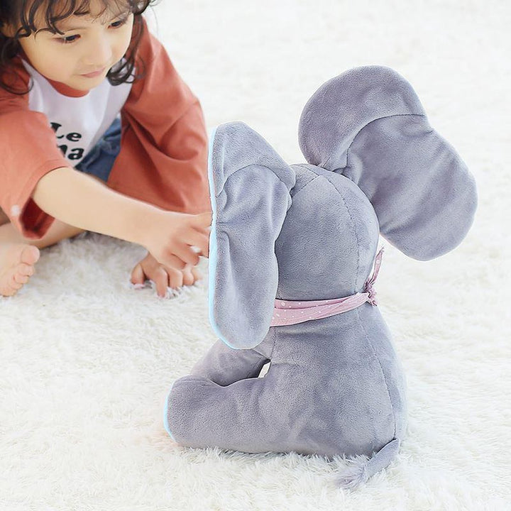 Kind spielt lachend mit Elefant Ellie, dem singenden Kuscheltier mit den lustigen Wackelohren.