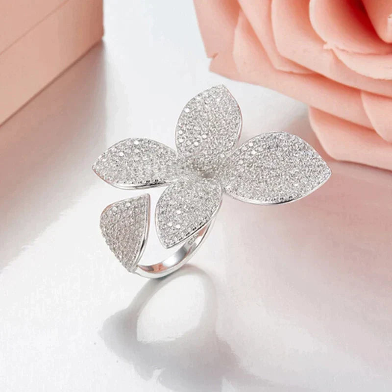Eleganter Damenring aus Silber mit Blumenmuster, verstellbar und funkelnden Zirkonia-Steinen.