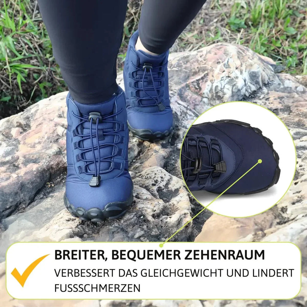 Person trägt blaue Barfußschuhe beim Wandern auf Felsen, Fokus auf breite Zehenbox.