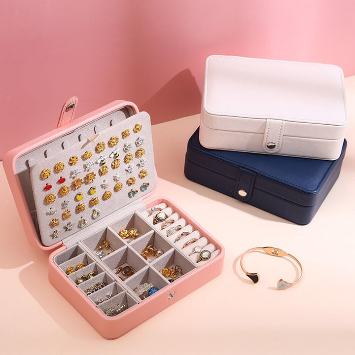Eleganter Leder Schmuckkasten mit Ringen und Ohrringen auf Kommode, ordentliche Schmuckaufbewahrung.