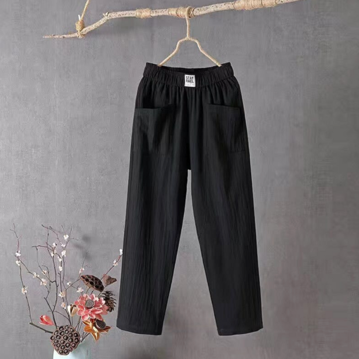 Lachende Frau trägt elegante schwarze Leinenhose Livia mit elastischem Bund im Sommerpark.