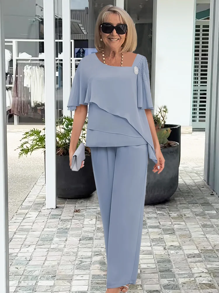 Reife Dame trägt blaues Hochzeitsgast-Set mit Sonnenbrille und Clutch im Freien.
