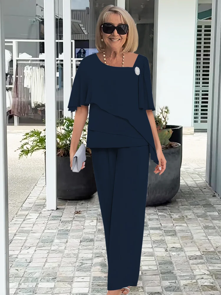 Detailansicht der Bluse mit geschwungenen Lagen und dezenter Brosche des Damen Sets.