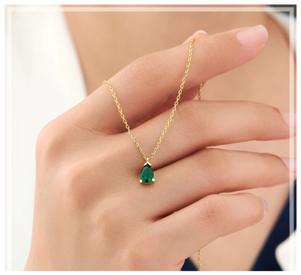 Funkelnde Damen-Halskette, goldfarben, mit großem Smaragd-Tropfen und kleinen Strass-Akzenten, Modeschmuck.