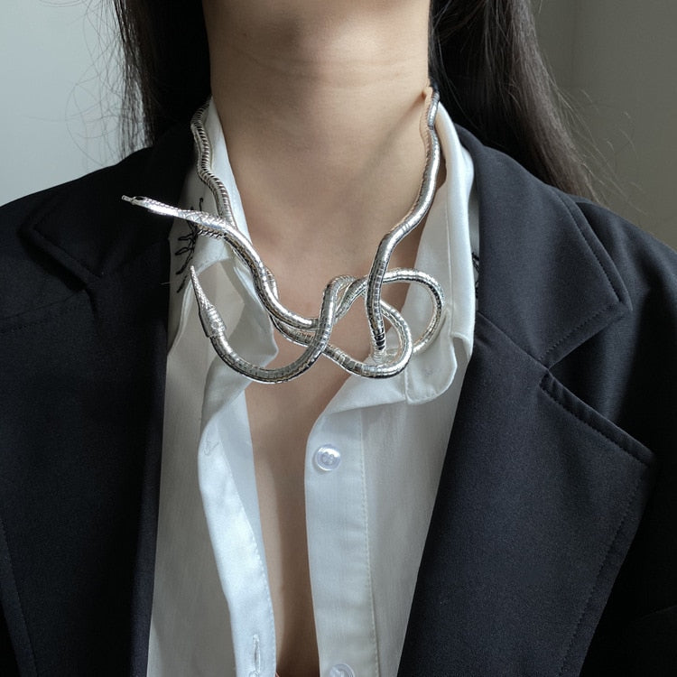 Dame präsentiert elegante goldfarbene Schlangenkette aus Metall als auffälliges Fashion-Statement.