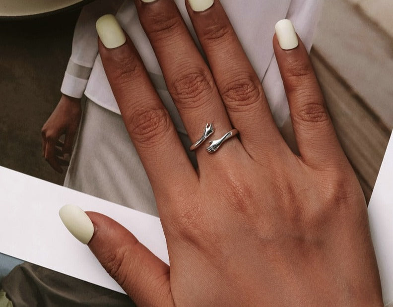 Glänzender Silber Damen Umarmungsring am Finger, eleganter Symbolschmuck für besondere Anlässe & Alltag.