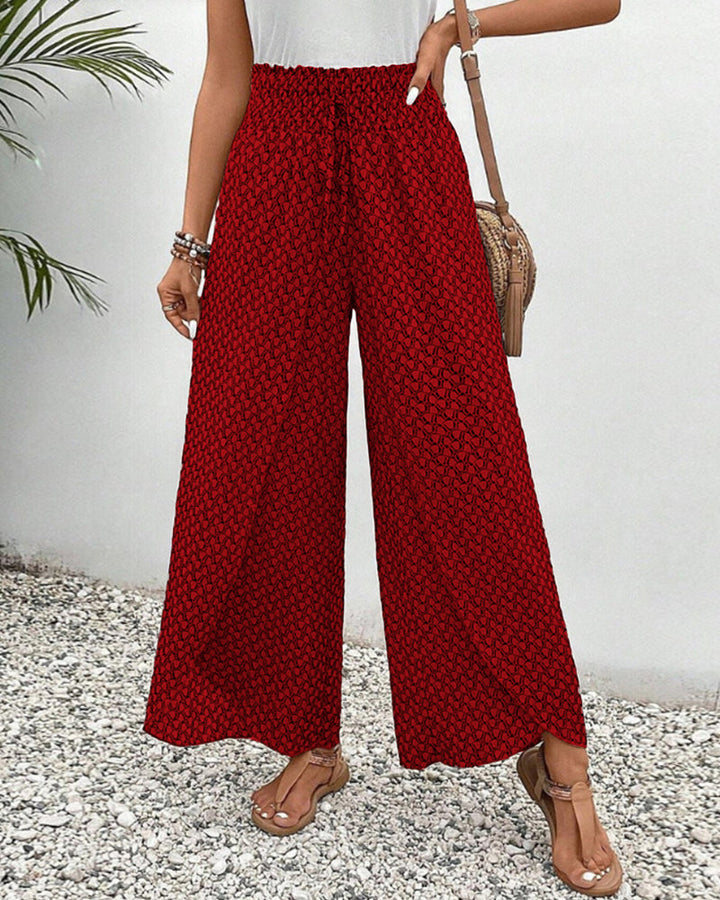 Lässige Damenhose mit weitem Bein und Muster. Geometrisches Design in Rot, Grün, Schwarz. Ideal für Frühling.