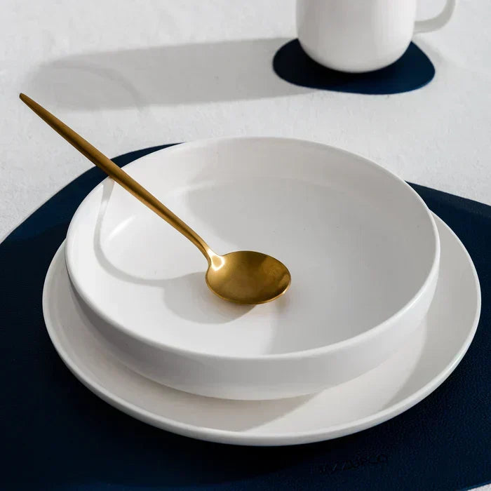 Hochwertiges Goldbesteck, mattiert und minimalistisch, arrangiert auf einer modernen Tafel.