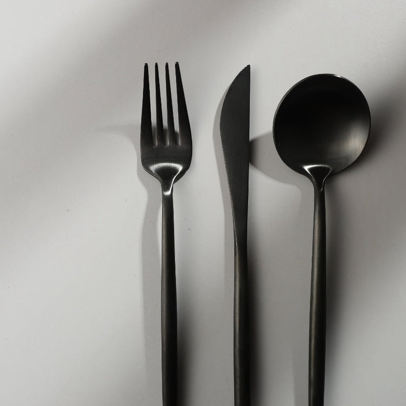 Minimalistische Teelöffel und Kuchengabeln aus dem Besteckset in mattem Schwarz.