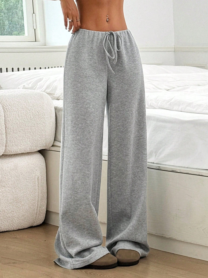 Frau entspannt in weicher, gerippter Loungewear-Hose mit Kordelzug, genießt Komfort & Stil zu Hause.