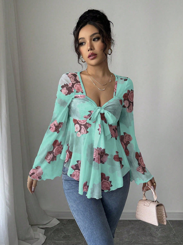 Nahaufnahme des transparenten Stoffes und floralen Prints der Babydoll-Bluse mit Knotenfront.