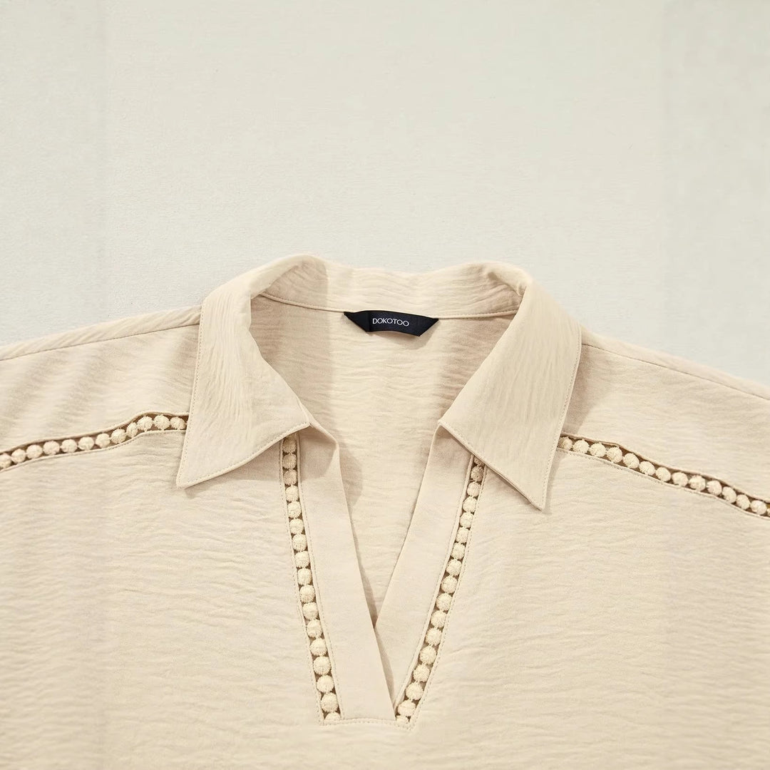 Weiße Frauenbluse mit floraler Spitze, tiefem V-Ausschnitt und hochkrempelbaren Ärmeln. Vielseitig kombinierbar.