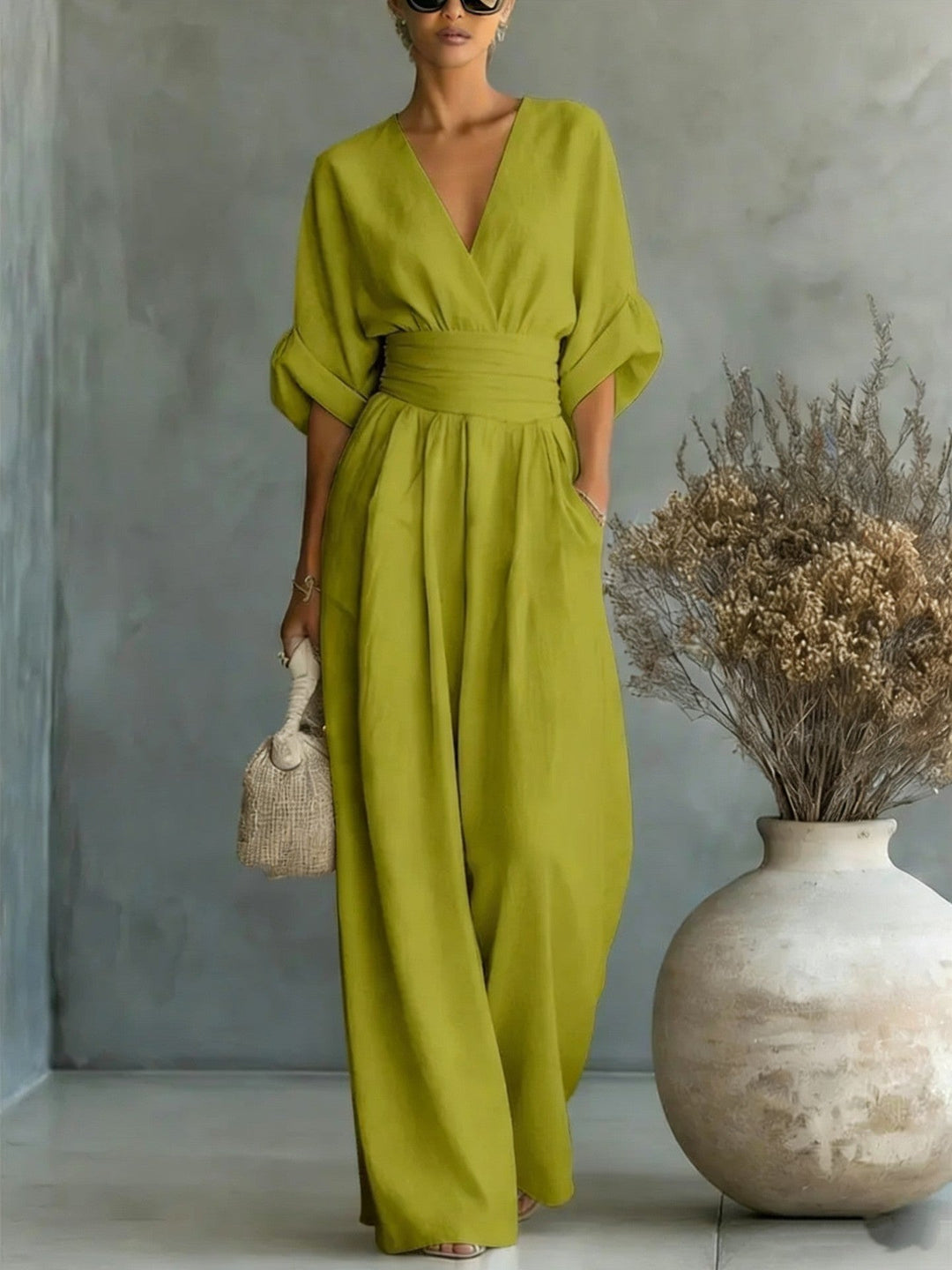 Model trägt grünen Damen Jumpsuit mit V-Ausschnitt & weitem Bein. Betont die fließende Eleganz.