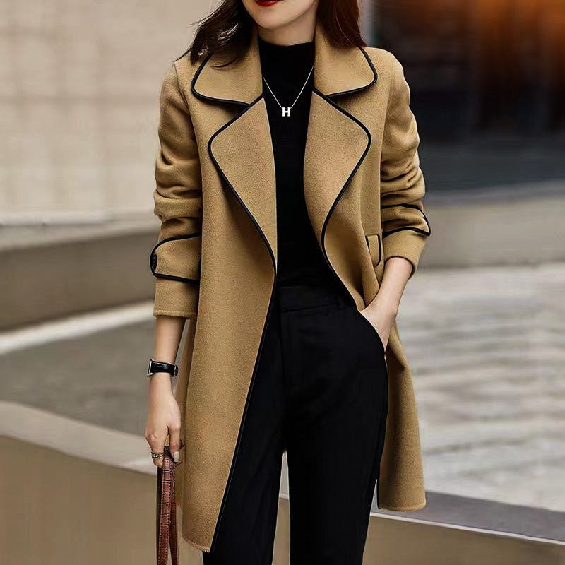 Modell trägt eleganten Damen A-Linien Mantel mit Kontrastdetails, Taillengürtel. Herbst- & Frühlingsmode.
