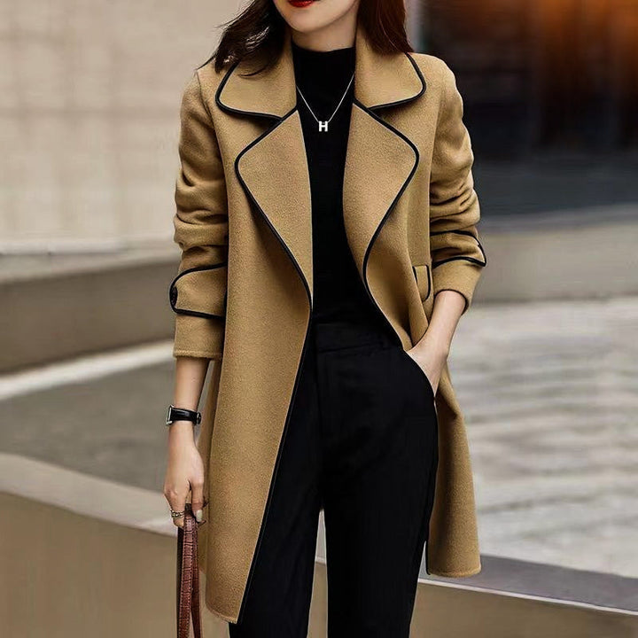 Modell trägt eleganten Damen A-Linien Mantel mit Kontrastdetails, Taillengürtel. Herbst- & Frühlingsmode.