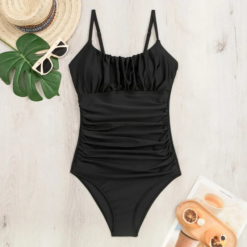 Aktive Dame im schwarzen Monokini am Strand. Bequemer, figurformender Badeanzug mit Bauchkontrolle für Sommeraktivitäten.