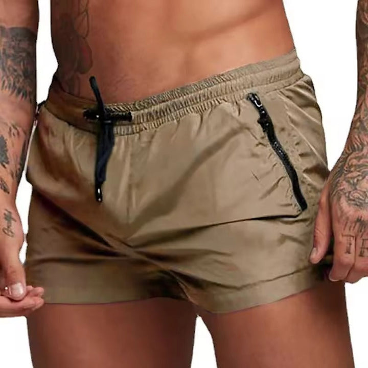Mann steht am Strand in blauen Herren Schwimmshorts. Komfortable, schnell trocknende Badehose für den Sommer.