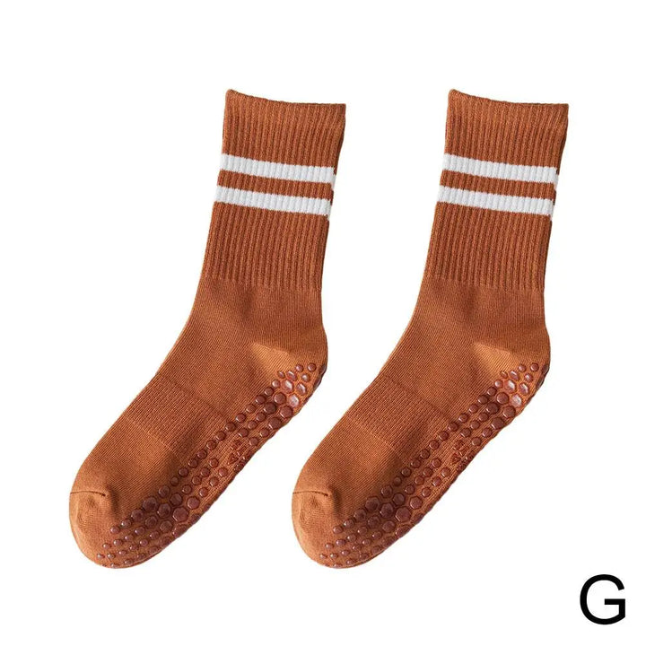 Eine Person trägt halbhohe Unisex Sportsocken mit Antirutsch-Grip beim Yoga. Sicherer Halt auf der Matte.