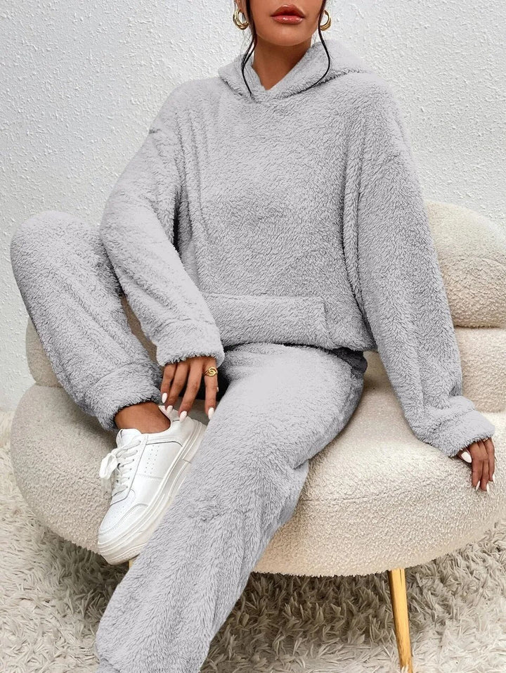Eine Frau entspannt im kuscheligen Damen Teddy-Hausanzug mit Kapuze, warme Wintermode.