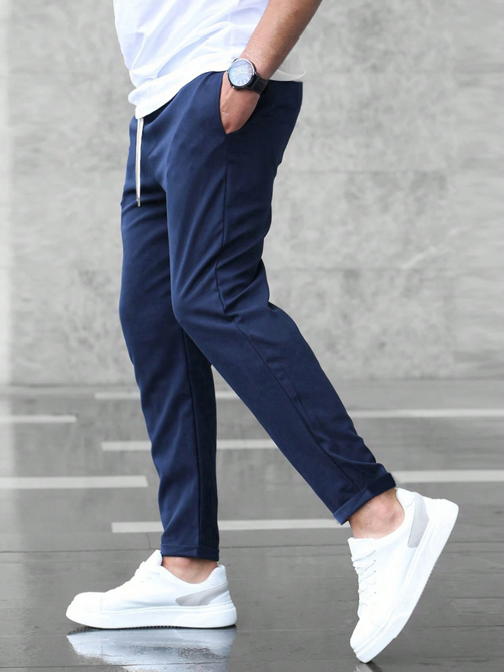 Mann trägt schwarze Slim Fit Herrenhose mit Tunnelzug, seitliche Ansicht, moderne Passform, hohe Bewegungsfreiheit.