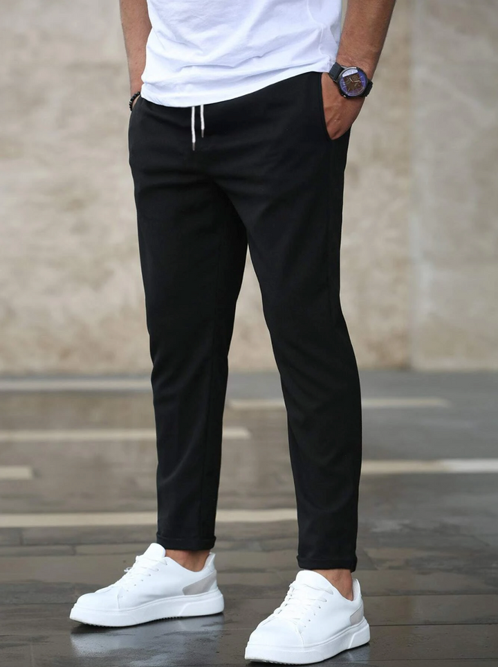 Gefaltete schwarze Herren Slim Fit Stoffhose mit Tunnelzug, Produktansicht, vielseitige Alltagshose, Komforthose.