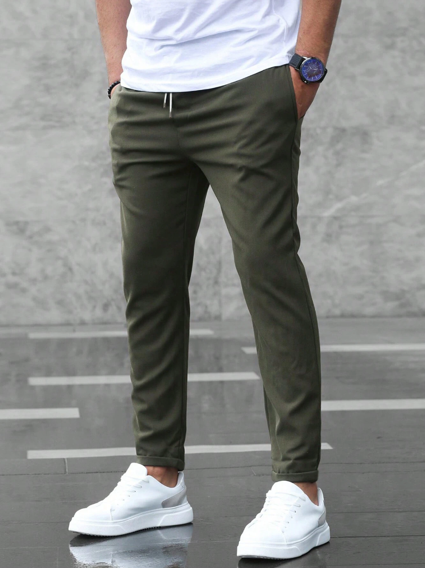 Mann entspannt sitzend in moderner Slim Fit Herrenhose mit Tunnelzug, bequeme Freizeithose für stilvolle Herren.