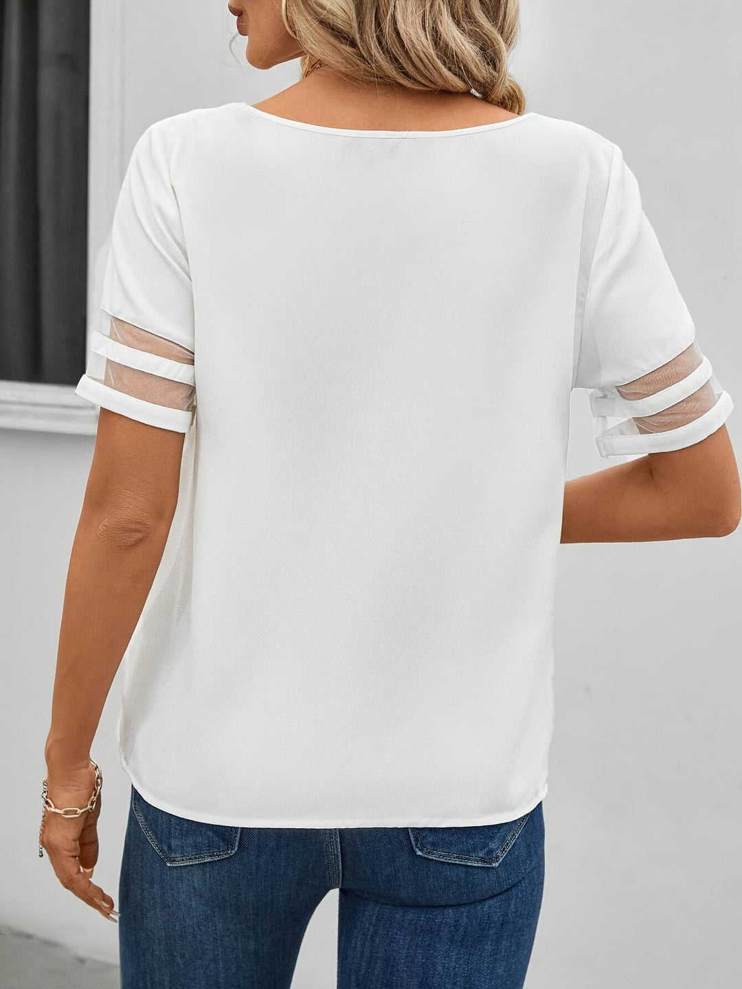 Detailansicht der Damenbluse: asymmetrischer Ausschnitt, zartes Blumenmuster, luftige Sommermode.