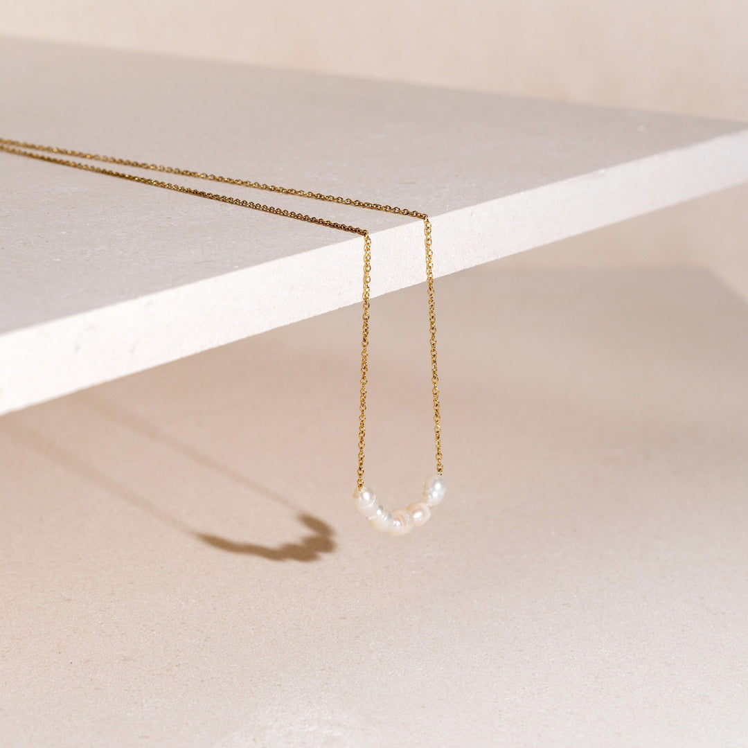 Nahaufnahme der goldenen Damenkette mit 5 echten, glänzenden Süßwasserperlen. Hypoallergener Perlenschmuck.