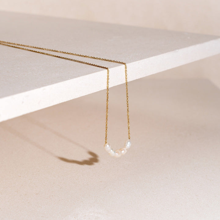 Nahaufnahme der goldenen Damenkette mit 5 echten, glänzenden Süßwasserperlen. Hypoallergener Perlenschmuck.