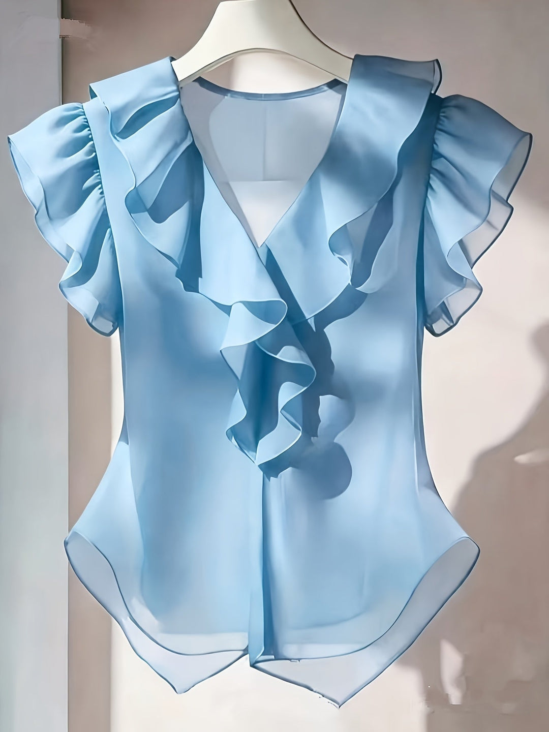 Detailaufnahme der Rüschen und des V-Ausschnitts einer weißen Damenbluse.