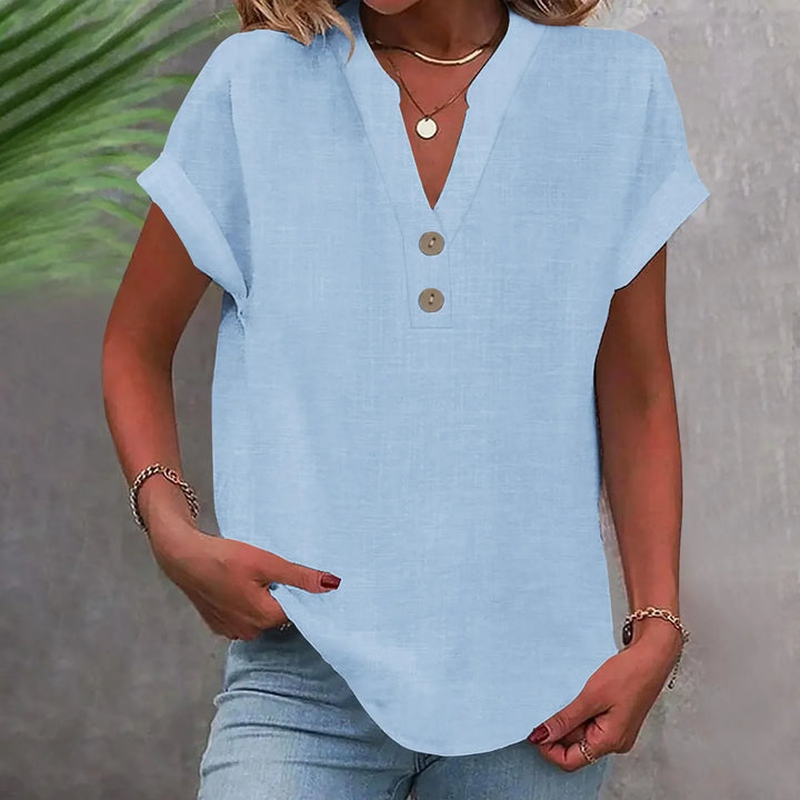 Damenbluse in hellem Farbton mit V-Ausschnitt. Knöpfe zieren die Front, ideal für elegante Anlässe.