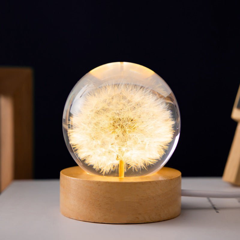 Elegante LED-Lampe: Kristallkugel mit getrockneten Blumen, Lichteffekt & Natur-Holzfuß.