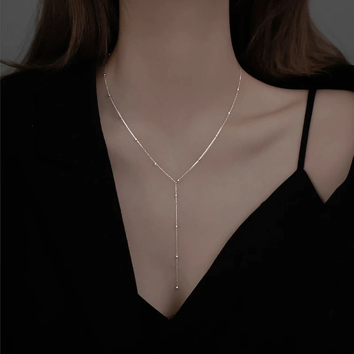 Elegante silberbeschichtete Damenhalskette mit V-Form und zarten Quasten. Schlüsselbeinkette, stilvoller Modeschmuck für Frauen.