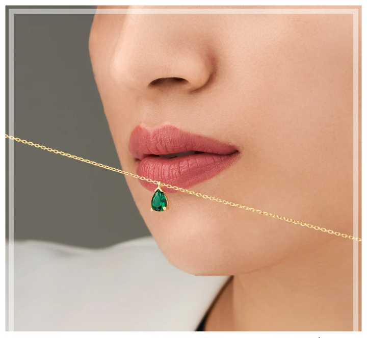 Stilvolle Damen-Halskette mit goldfarbener Kette und einem großen, eleganten Smaragd-Tropfenanhänger.