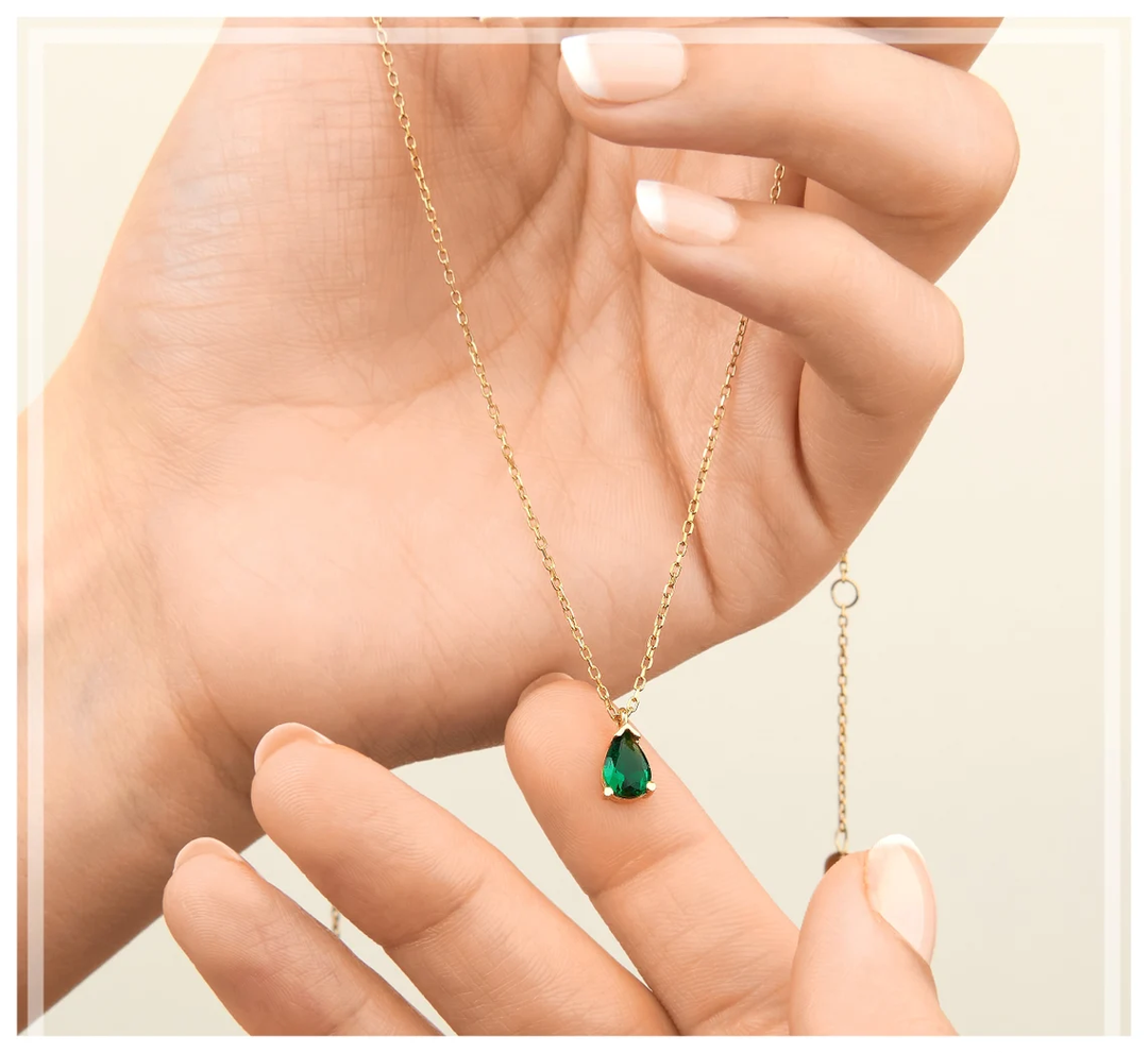 Luxuriöse Damen-Halskette, goldfarben, mit einem strahlenden Smaragd-Tropfenanhänger. Perfekte Geschenkidee.