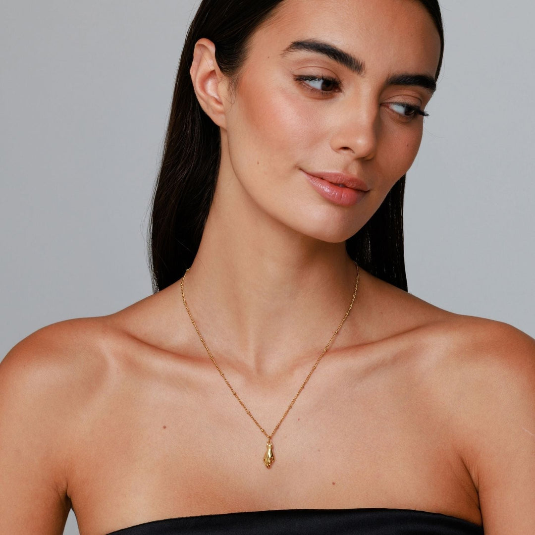 Goldfarbene Damen Halskette mit einzigartigem Schutz Hand Anhänger & grünem Zirkon. Moderner Edelstahlschmuck.