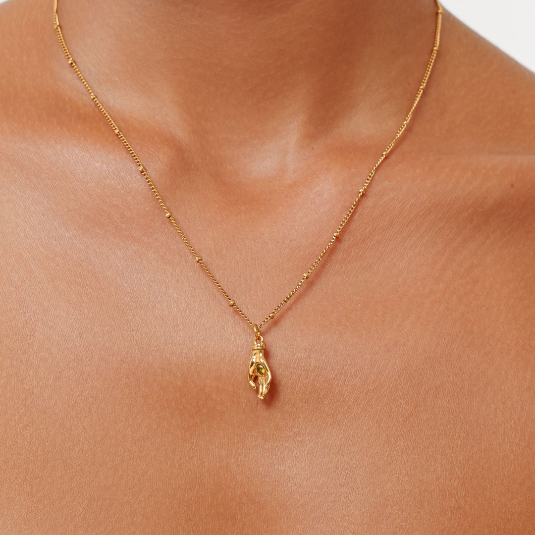 Goldfarbene Damenhalskette mit Schutz Hand Anhänger & grünem Zirkon. Eleganter Symbolschmuck aus Edelstahl.