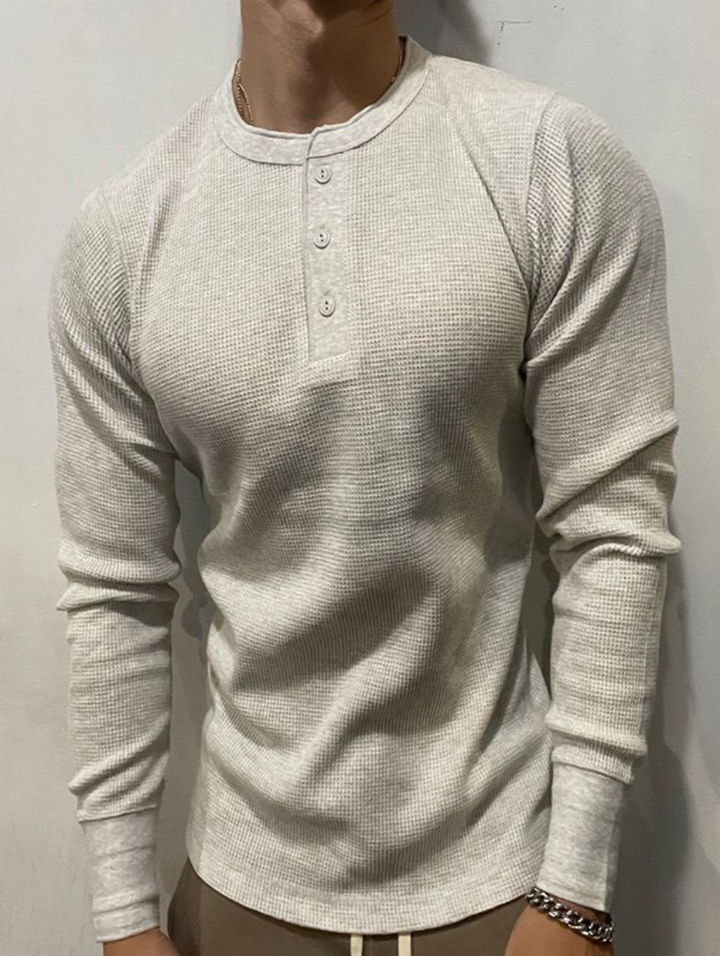 Eng anliegendes Herren Langarm-T-Shirt mit Henley-Kragen und Waffelstruktur, modisch.