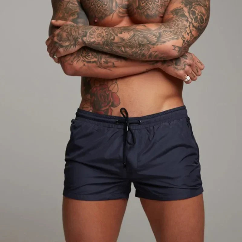 Mann trägt blaue Herren Badehose beim Sprung ins Meer. Komfortable Schwimmshorts, ideal für Wassersport & Strandurlaub.