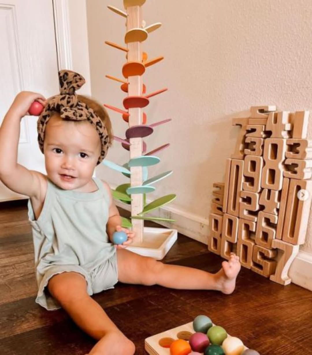 Kinder spielen mit dem hölzernen Klangbaum, beobachten Kugeln beim Fallen und lauschen den harmonischen Tönen.