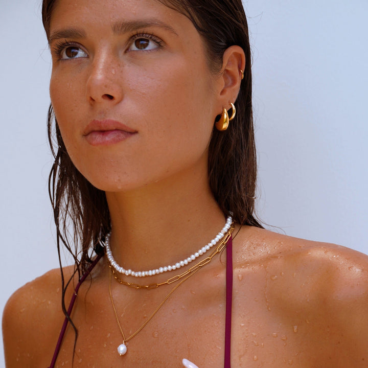 Nahaufnahme einer Damen Goldkette mit glänzenden Süßwasserperlen, modern & hypoallergen.