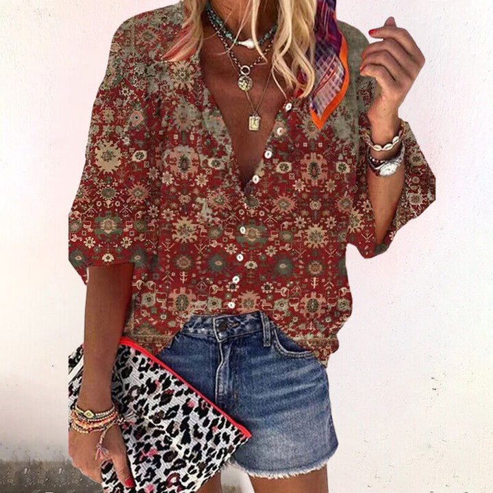 Frau trägt elegante Sommerbluse mit farbigem Blumenprint und weiten Ärmeln. Perfekt für den Boho-Look.
