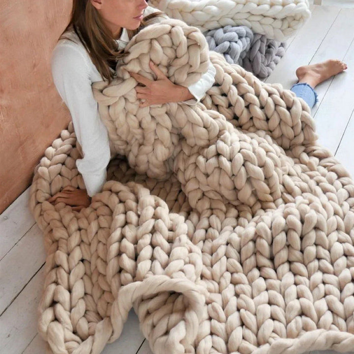 Fertige, handgestrickte Decke aus dickem XL chunky Garn auf einem Sofa.